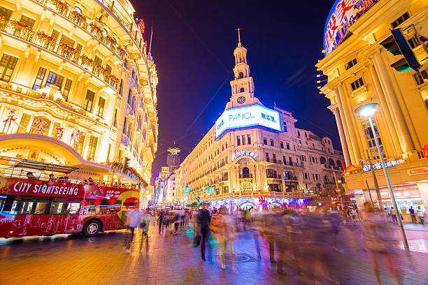 Shanghai, Сhina - Jun 21, 2013: There are many tourists on Nanjing Road Pedestrian Street at night, going shopping or sightseeing. There are also sightseeing buses shuttling among the tourists. Nanjing Road is Shanghai's most famous shopping street. It is located in the city center and has numerous stores for shopping.