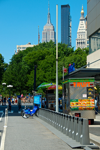 New York City, USA - June 19, 2013: A Citi Bike bicycle sharing station at 14th Street & Broadway, Manhattan where the Empire State Building is seen uptown at 34th Street.