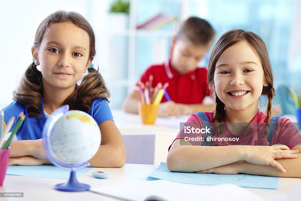 Cute kids Portrait of cute school girls sitting at their desk Beautiful People Stock Photo