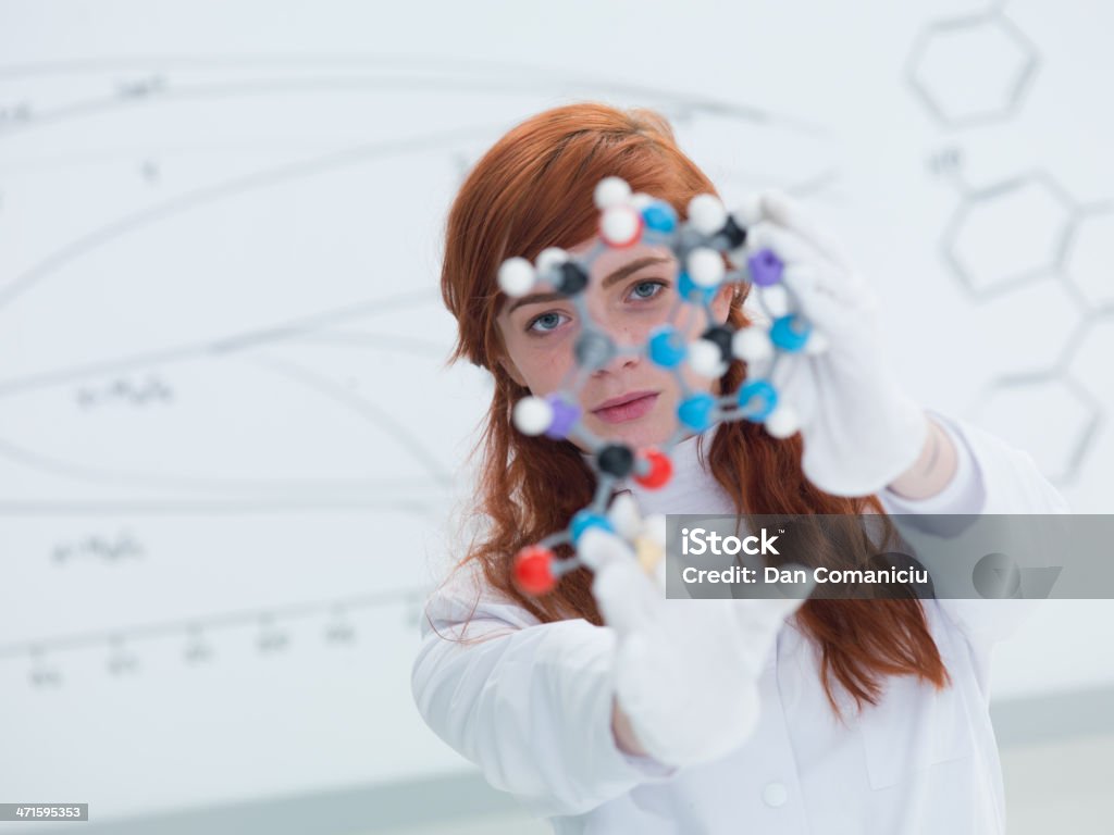 student dmt molecule analysis general-view  of a student in a chemistry lab looking in the camera and holding in hands and analyzing DMT molecular model and a white board on the background Fashion Stock Photo