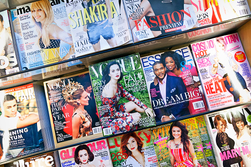 New York City, USA - June 22, 2013: Stack of popular magazines on the outside of the street side newsstand on Broadway Upper West. Vogue, Cosmopolitan, Glamour and Essence can be seen.