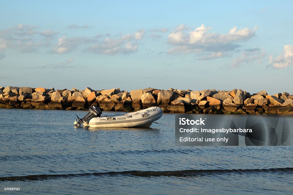 Boat Norfolk, Va. USA - June 1, 2013: On a summer afternoon along the Chesapeake Bay in Norfolk, Virginia a small boat sits in shallow water among the jettee on this scenic day. Beach Stock Photo