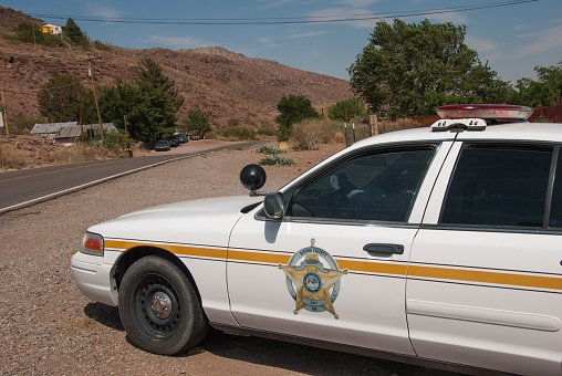 HIllsboro, New Mexico, USA - June 23, 2013: While this image appears to depict a sheriff's officer watching for speeders on a remote New Mexico highway, take another look. This is actually a \