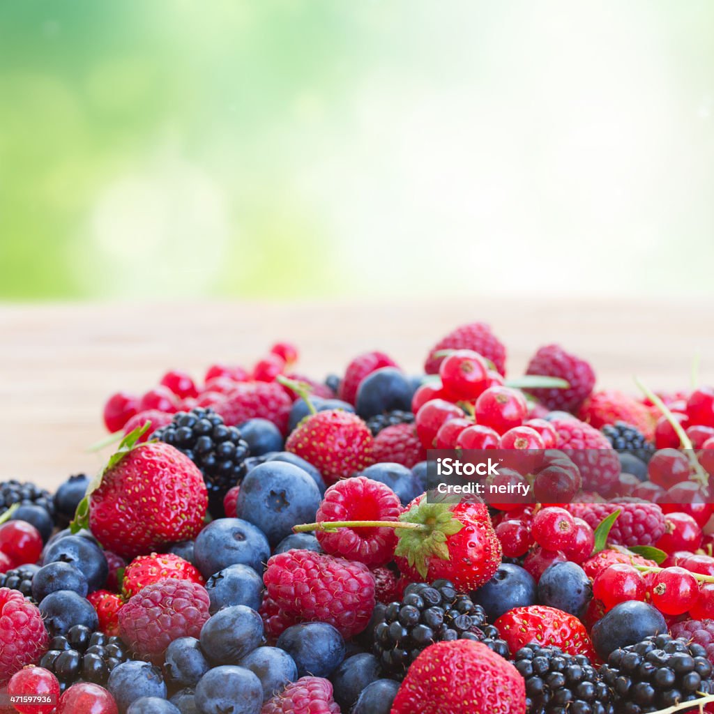 ripe  of  berries on table ripe of  berries on wooden table in garden  - blackberry, raspberry , red currant and blueberry Berry Fruit Stock Photo