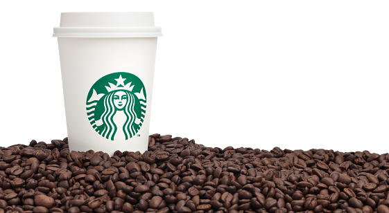 Taipei, Taiwan - February 3, 2013: This is a studio shot of a Starbucks cup of coffee on top of a pile of Starbucks brand coffee beans isolated on white.