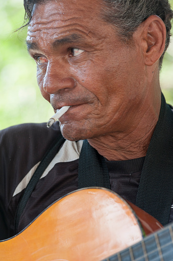 havana, Сuba - June 11, 2013: cuban man smoking a cigarette and playing the guitar  in downtown havana.