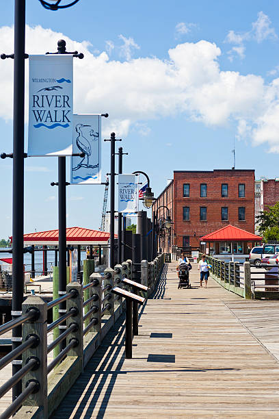 Wilmington, North Carolina, USA River Walk Wilmington, North Carolina, USA - June 20th, 2013:  The River Walk In Wilmington, North Carolina With A Couple Of People Pushing A Baby Carriage On The Promenade. cape fear stock pictures, royalty-free photos & images