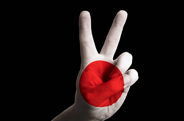 Hand with two finger up gesture in colored japan national flag as symbol of winning, victorious, excellent, - for tourism and touristic advertising, positive political, cultural, social management of country