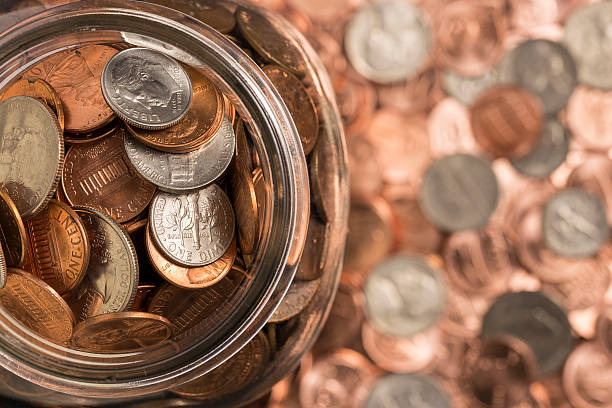 Coin Jar A jar of coins surrounded by coins. ten cents stock pictures, royalty-free photos & images