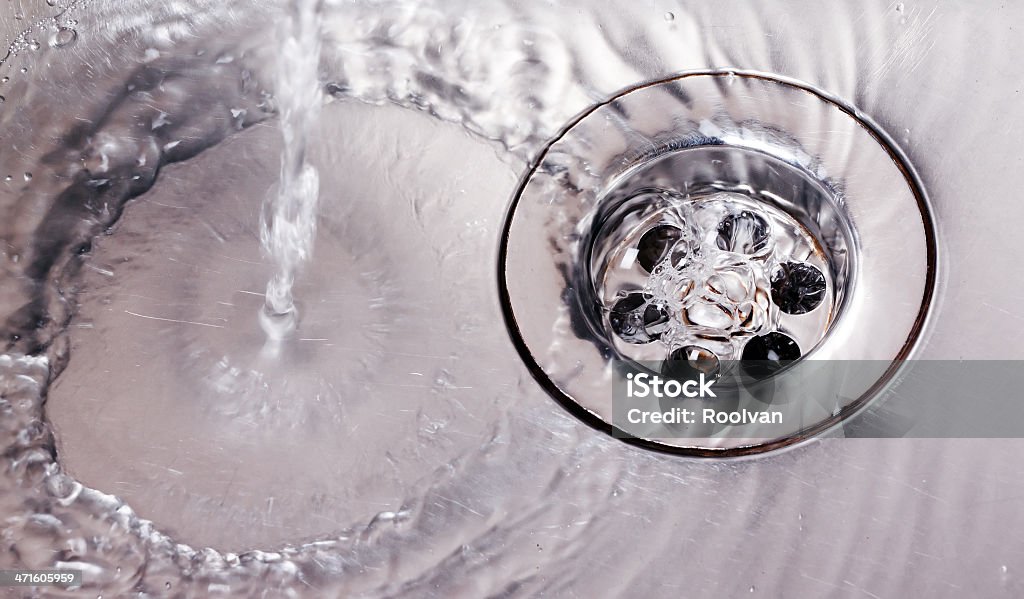 Water running down steel sink drain Stainless steel sink plug hole close up with water Drain Stock Photo