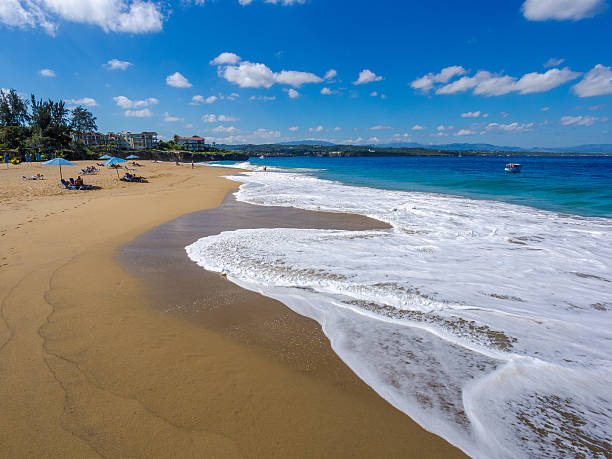 Sosua, Dominican Republic - February 25, 2013: Beach scene. People can be seen on the beach in the morning sitting under beach umbrellas in the distance at Sosua on the northern coast of the Dominican republic.