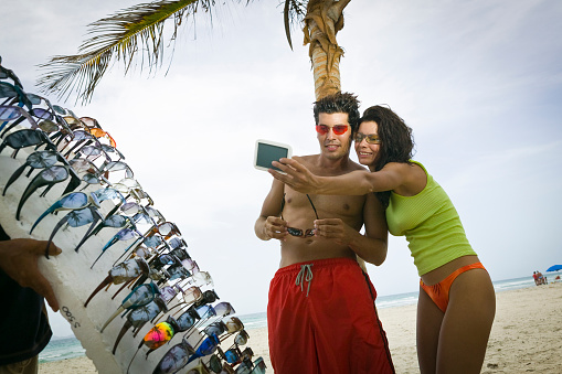 Couple trying on sunglasses at beach, Margarita Island, Venezuela