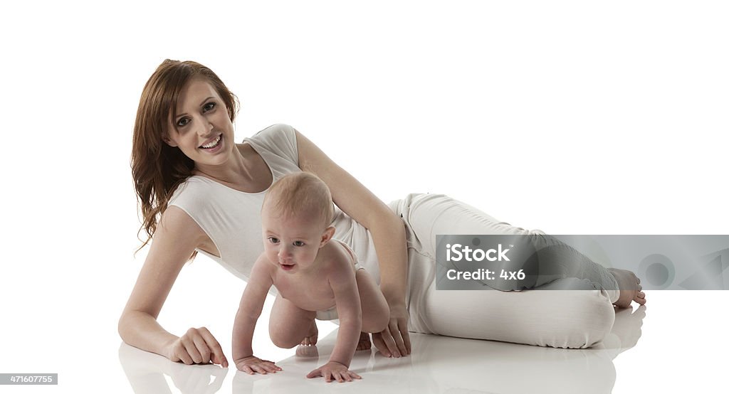Madre sonriente caer en el suelo con su bebé - Foto de stock de 20 a 29 años libre de derechos