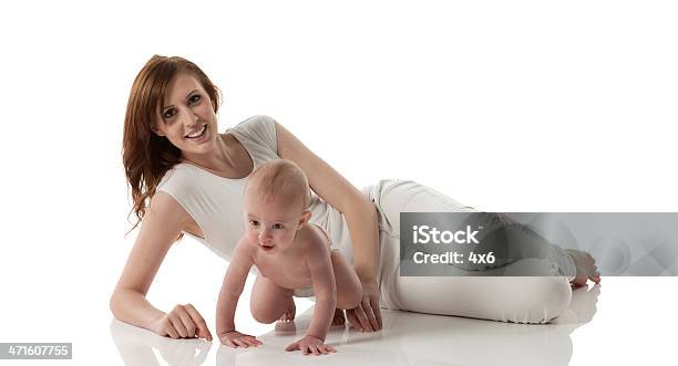Madre Sonriente Caer En El Suelo Con Su Bebé Foto de stock y más banco de imágenes de 20 a 29 años - 20 a 29 años, 6-11 meses, Acostado