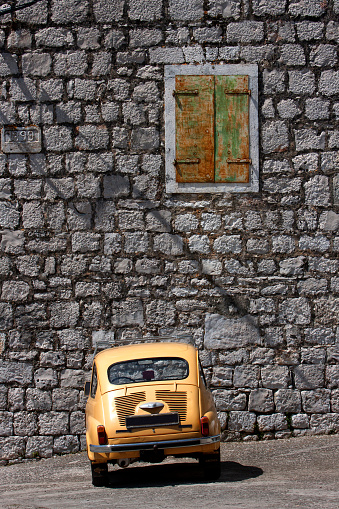 Donje Selo, island Solta, Croatia, orange old car Zastava 750 in front of stone facade