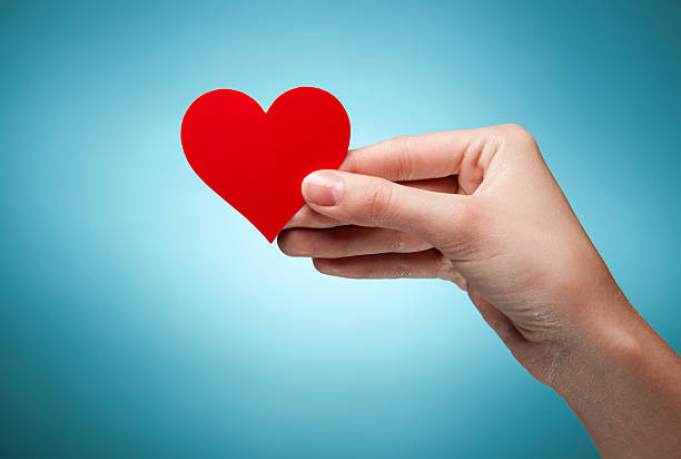 istock woman's hand holding symbol - red heart. Against blue background 471609367