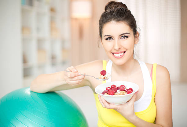 Young woman exercising at home and eating healthy.  