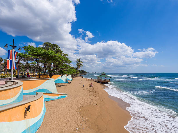Santo Domingo, Dominican Republic - February 23, 2013: People can be seen along the waterfront walkway and on the beach on a clear day with waves breaking on the shore line in an are known as the Malecon in Santo Domingo, capital of the Dominican Republic.
