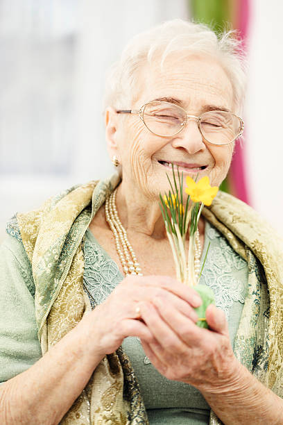 istock Smiling senior woman smelling a flower 471614197