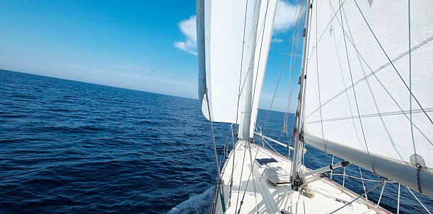 Yacht with white sails sailing towards the horizon stock photo