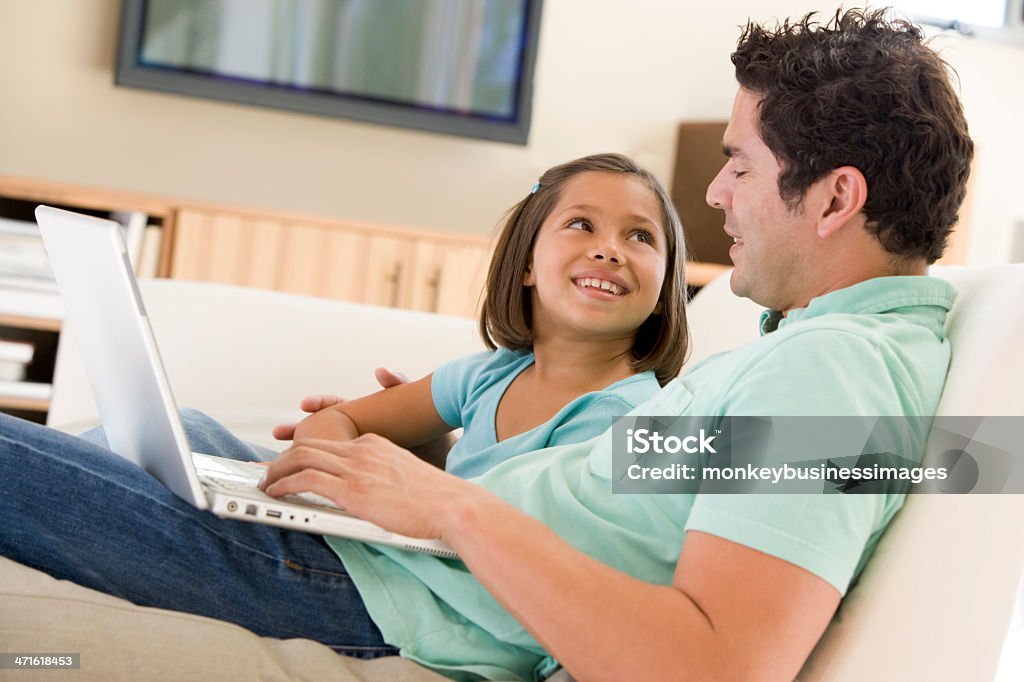 Homme et jeune fille dans la salle de séjour avec ordinateur portable souriant - Photo de Adulte libre de droits