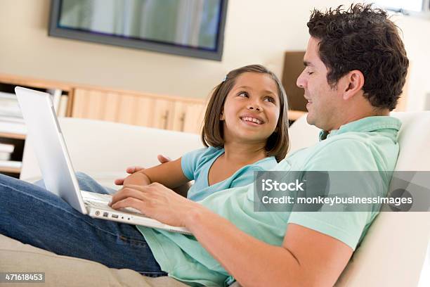 Foto de Homem Com A Menina Na Sala De Estar Com Laptop Sorrindo e mais fotos de stock de 30 Anos