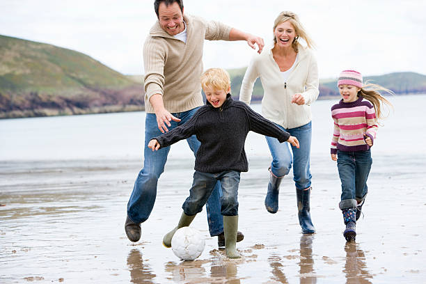 istock Family playing soccer at beach smiling 471618473