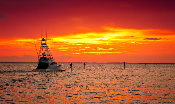 A ship at sea in the sunset with orange skies
