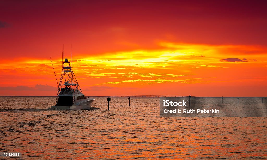 A ship at sea in the sunset with orange skies Large fishing boat going out for a sunset cruise in Destin, Florida Destin Stock Photo