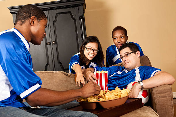 istock Relationships:  Multi-ethnic Football fans at home snacking and watching TV 471622461
