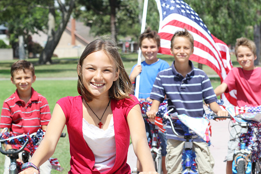 Five siblings (three of them triplets) stand with their just-decorated bikes in preparation for an upcoming patriotic bike parade.