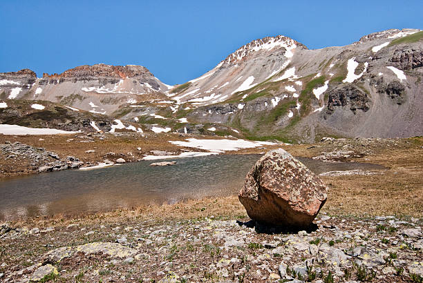 Glacial Erratic in Upper Ice Lakes Basin Large boulders known as glacial erratics, are evidence of past ice ages. These boulders are deposited by the constant downhill movement of the glacier and left exposed as the glacier recedes. This glacial erratic was found at Upper Ice Lake in the San Juan mountains of southern Colorado. The San Juans are a high altitude range of mountains that straddle the Continental Divide. This wide-open landscape, at 12,300, is well above timberline. This photograph was taken from Upper Ice Lake in the San Juan National Forest near Silverton, Colorado, USA. jeff goulden san juan mountains stock pictures, royalty-free photos & images