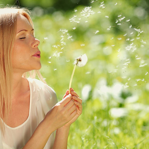 istock girl blowing on a dandelion 471625125
