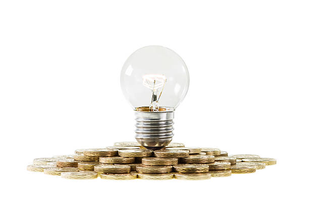 Research Funding Concept Light Bulb on Pile of Coins Research Funding and Investing in Innovation and Ideas Concept. A clear lightbulb with glowing filament on top of a pile of coins. tungsten image stock pictures, royalty-free photos & images