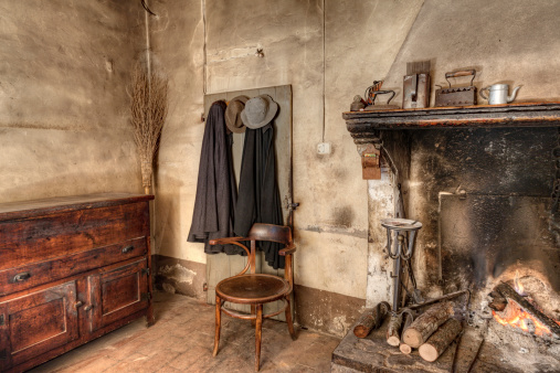 old times farmhouse - interior of an old country house with fireplace, kitchen cupboard, ancient mantles and straw broom