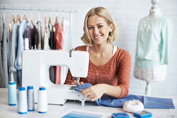 She's a terrific tailor A beautiful young seamstress sitting and sewing at a sewing machine woman stitching stock pictures, royalty-free photos & images