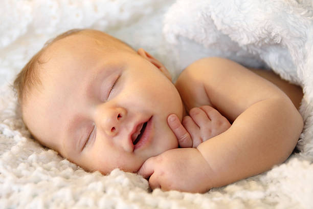 sonriente niña bebé recién nacido durmiendo envuelto en una manta blanco - 5 month old fotografías e imágenes de stock