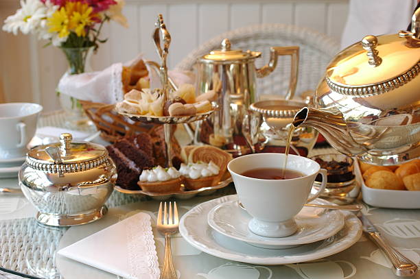 Tea being poured into a cup on a table set for afternoon tea Typical English Afternoon Tea. british culture stock pictures, royalty-free photos & images