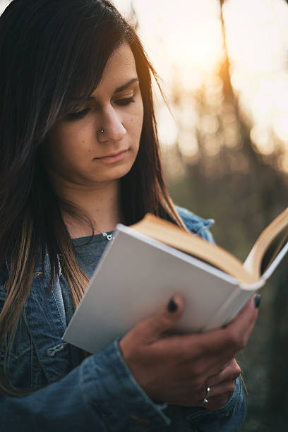 istock Young girl reading book outdoor 471636766