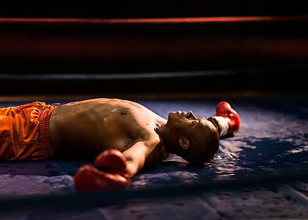 Knockout Boxer knocked out laying on the mat with his arms stretched out. knockout stock pictures, royalty-free photos & images