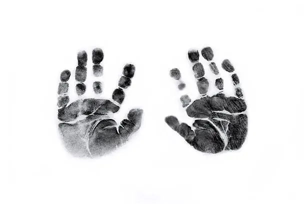 Photograph of Newborn baby handprints in black ink on white paper.