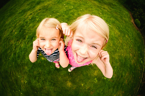 Funny portrait of girls playing together in park. Horizontal Fisheye Shot. Please checkout our lightboxes 