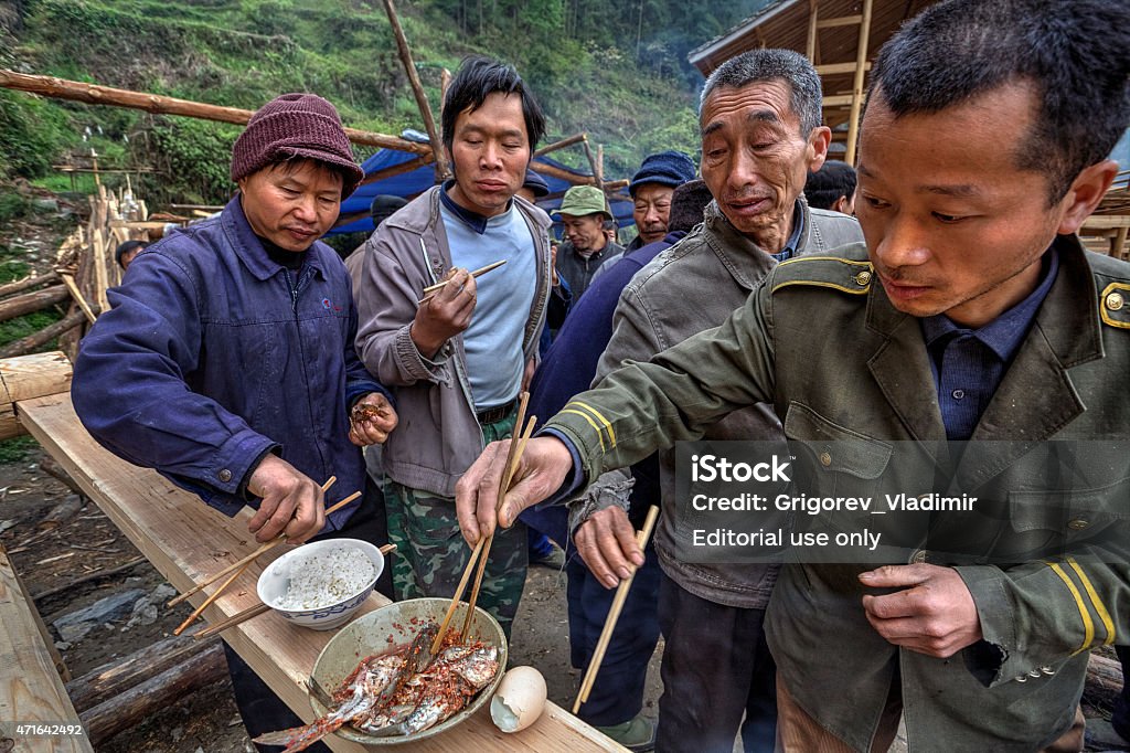 Sharing food on a rural celebration, local people farmers, China Langde Village, Guizhou, China - April 16, 2010: Eating together at village celebration, local residents, farmers peasants celebrating Start of construction of a new farm house. 2015 Stock Photo