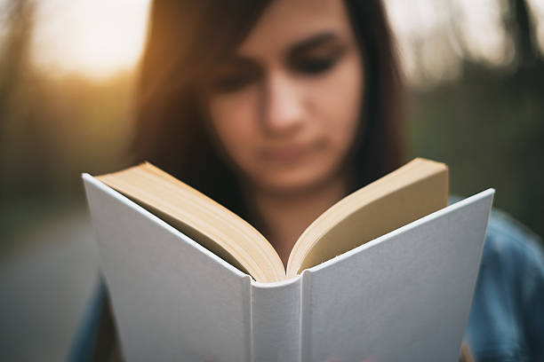 istock Young girl reading book outdoor 471643896