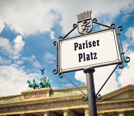 A sign for Pariser Platz in front of the iconic quadriga statue on top of the Brandenburg Gate in central Berlin.