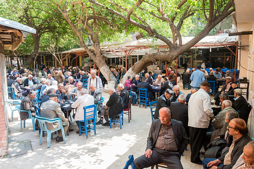 Adana, Turkey - April 18, 2015: Tea houses are most common places only male persons going on the Turkey. Senior Turkish men talking, drinkinking tea and playing cards and okey together. In Turkish language tea house called as kahvehane.