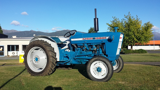 Te Anau, New Zealand- January 25, 2015: An old blue Ford 2000 tractor on a public green in New Zealand for sale