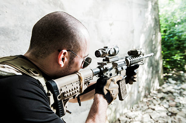 Young Caucasian Modern Mercenary Soldier Aiming with Assault Rifle stock photo