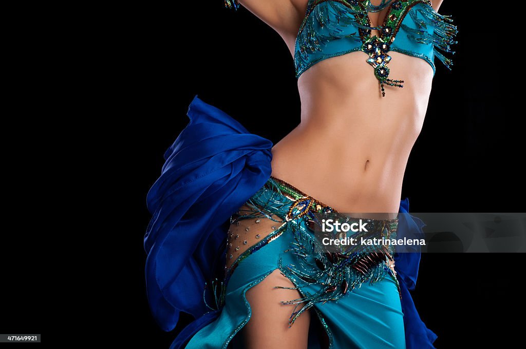 Torso of a  Bellydancer Shaking her Hips Torso of a female belly dancer wearing a teal blue costume and shaking her hips. Isolated on a black background. Belly Dancing Stock Photo