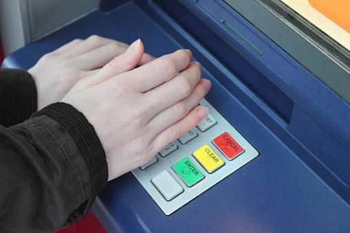 Photo showing PIN numbers being hidden with hands at a cashpoint (ATM - automatic teller machine), in case anyone is watching them being entered.  Cash machine fraud is an ongoing problem for banks, with a growing percentage of debit and credit cards being cloned or stolen.
